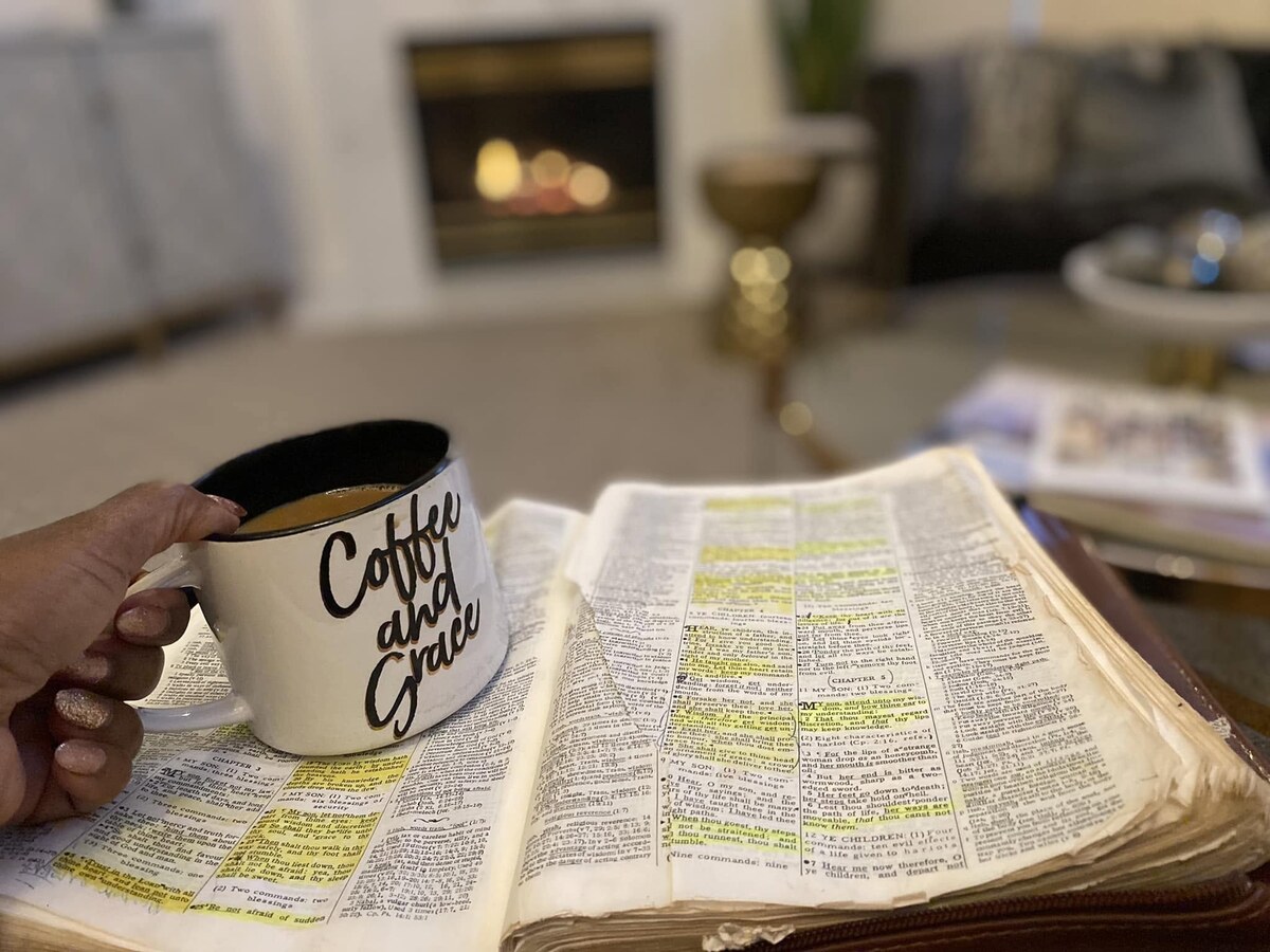 An open Bible with highlighted passages in Proverbs beside a coffee mug